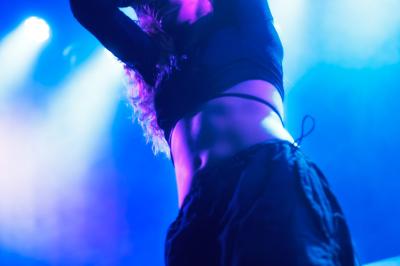 Voiture sportive bleue stationnée sur une place pavée devant un monument en bronze et des bâtiments historiques.