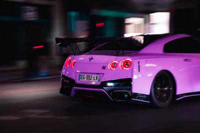 Voiture sportive bleue stationnée sur une place pavée devant un monument en bronze et des bâtiments historiques.