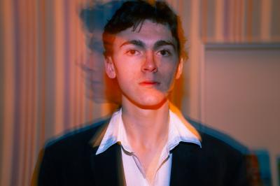 Voiture sportive bleue stationnée sur une place pavée devant un monument en bronze et des bâtiments historiques.