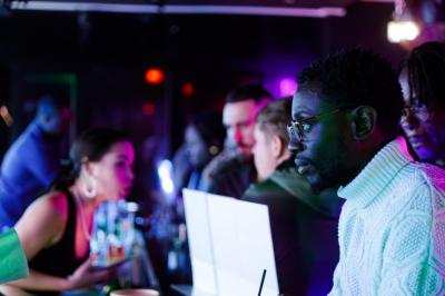 Voiture sportive bleue stationnée sur une place pavée devant un monument en bronze et des bâtiments historiques.