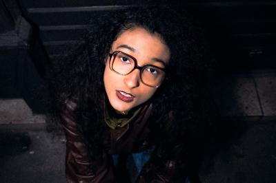 Voiture sportive bleue stationnée sur une place pavée devant un monument en bronze et des bâtiments historiques.