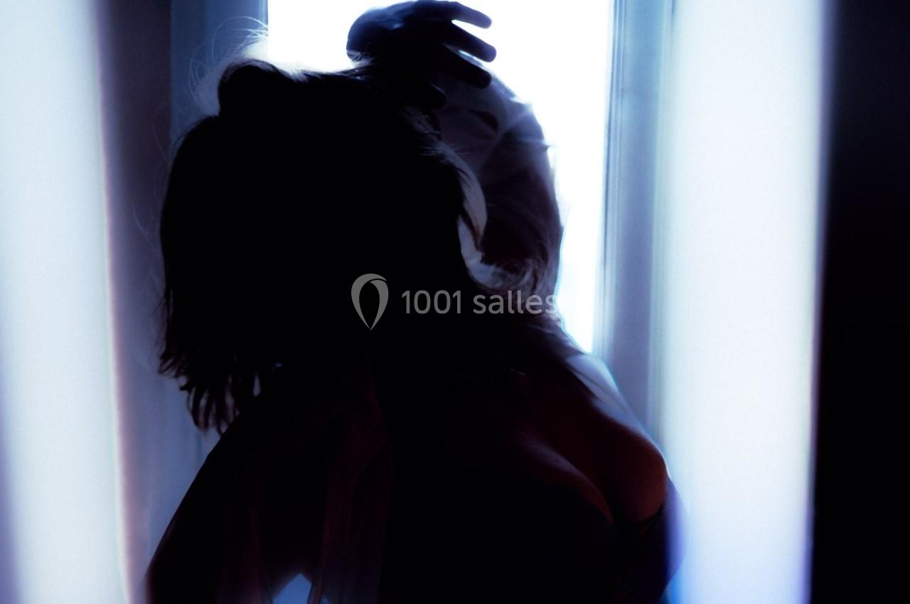 Silhouette d'une personne dans une lumière tamisée, devant une fenêtre lumineuse, créant un contraste marqué.