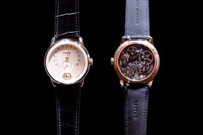 Femme assise sur un banc en extérieur, portant un sweat noir, avec un ciel bleu et des bâtiments en arrière-plan.