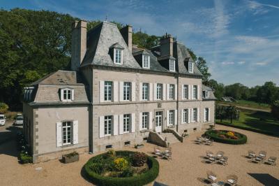 Miniature Location salle Tréflévénez (Finistère) - Château de Kérézellec #6 Un couple de mariés marche vers un château en pierre avec des volets blancs, entouré de quelques invités.
