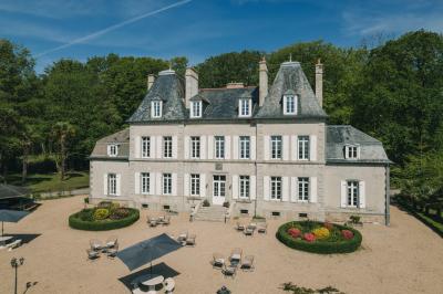 Miniature Location salle Tréflévénez (Finistère) - Château de Kérézellec #5 Un couple de mariés marche vers un château en pierre avec des volets blancs, entouré de quelques invités.