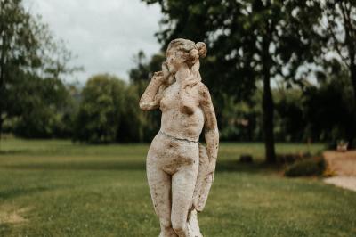 Miniature Location salle Tréflévénez (Finistère) - Château de Kérézellec #11 Un couple de mariés marche vers un château en pierre avec des volets blancs, entouré de quelques invités.
