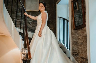 Miniature Location salle Tréflévénez (Finistère) - Château de Kérézellec #13 Un couple de mariés marche vers un château en pierre avec des volets blancs, entouré de quelques invités.