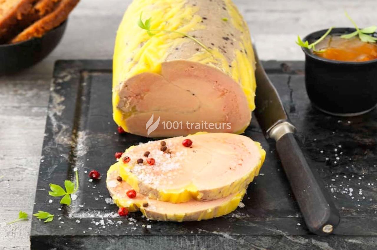 Bloc de foie gras tranché sur une planche avec couteau, accompagné de pain, confiture et grains de poivre.