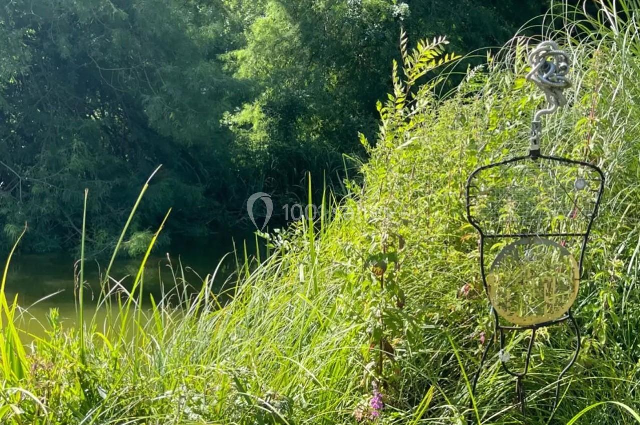 Un piège à poissons suspendu près d'une rivière entourée de végétation dense et verdoyante.