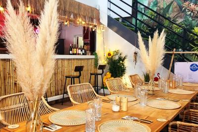 Assiette gastronomique avec un jarret d'agneau, purée de patate douce, gratin et fleurs comestibles, sur une nappe blanche.