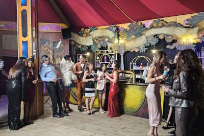 Assiette gastronomique avec un jarret d'agneau, purée de patate douce, gratin et fleurs comestibles, sur une nappe blanche.