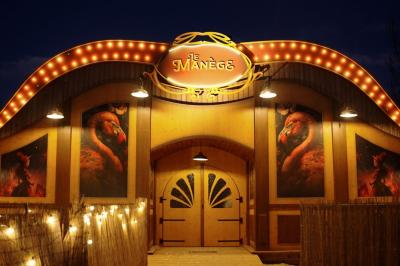 Assiette gastronomique avec un jarret d'agneau, purée de patate douce, gratin et fleurs comestibles, sur une nappe blanche.
