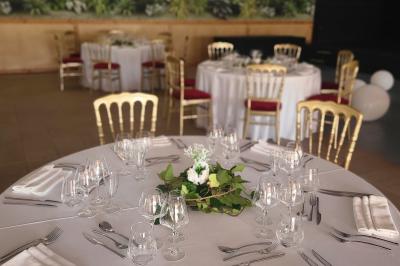 Assiette gastronomique avec un jarret d'agneau, purée de patate douce, gratin et fleurs comestibles, sur une nappe blanche.