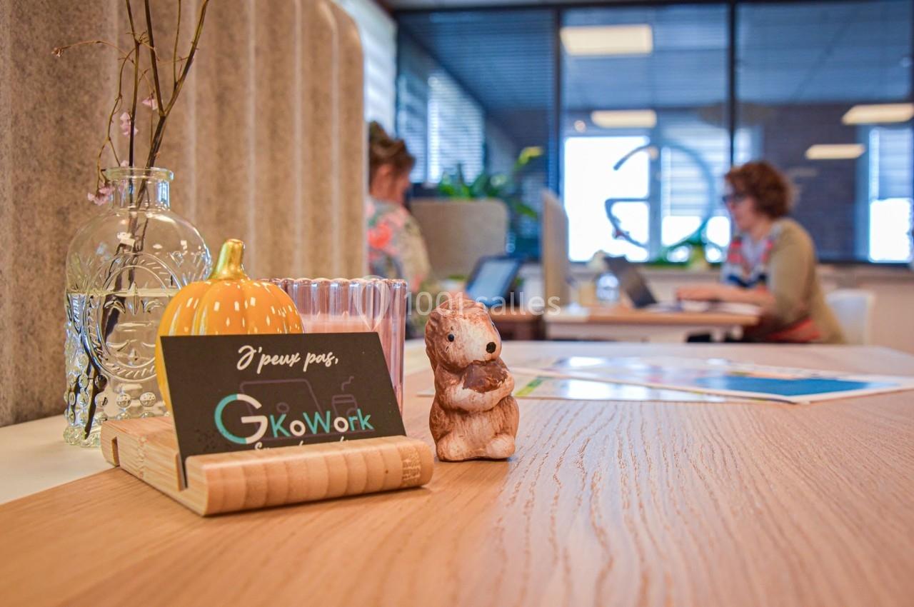 Un bureau partagé avec des personnes travaillant sur des ordinateurs en arrière-plan et une décoration sur une table.