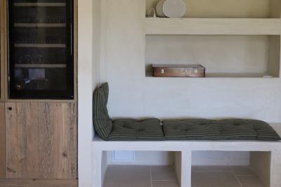 Deux chaises longues en bois et tissu rouge posées sur une terrasse en pierre, adossées à un mur en pierre.