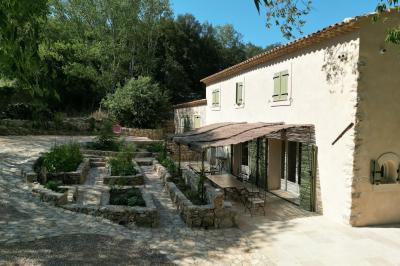 Deux chaises longues en bois et tissu rouge posées sur une terrasse en pierre, adossées à un mur en pierre.