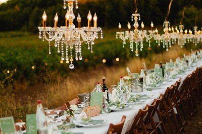 Un couple en tenue de mariage marche main dans la main dans un vignoble, la mariée levant un bouquet.
