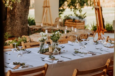 Un couple en tenue de mariage marche main dans la main dans un vignoble, la mariée levant un bouquet.