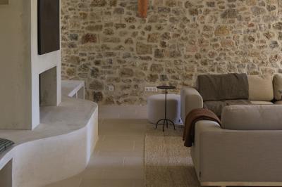 Deux chaises longues en bois et tissu rouge posées sur une terrasse en pierre, adossées à un mur en pierre.