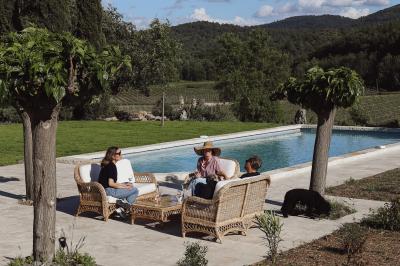 Deux chaises longues en bois et tissu rouge posées sur une terrasse en pierre, adossées à un mur en pierre.