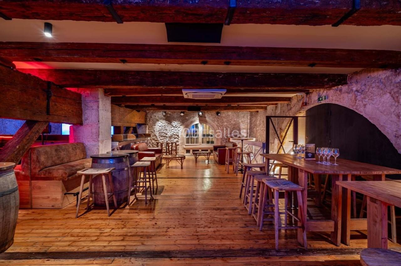 Salle chaleureuse avec poutres apparentes, murs en pierre, parquet en bois et mobilier rustique, ambiance conviviale.