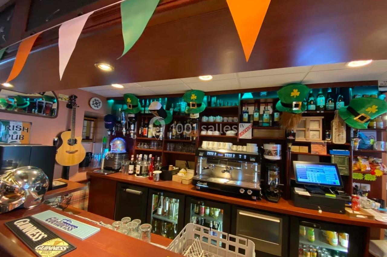 Intérieur d'un bar décoré sur le thème irlandais avec des chapeaux verts, guirlandes et instruments accrochés au mur.