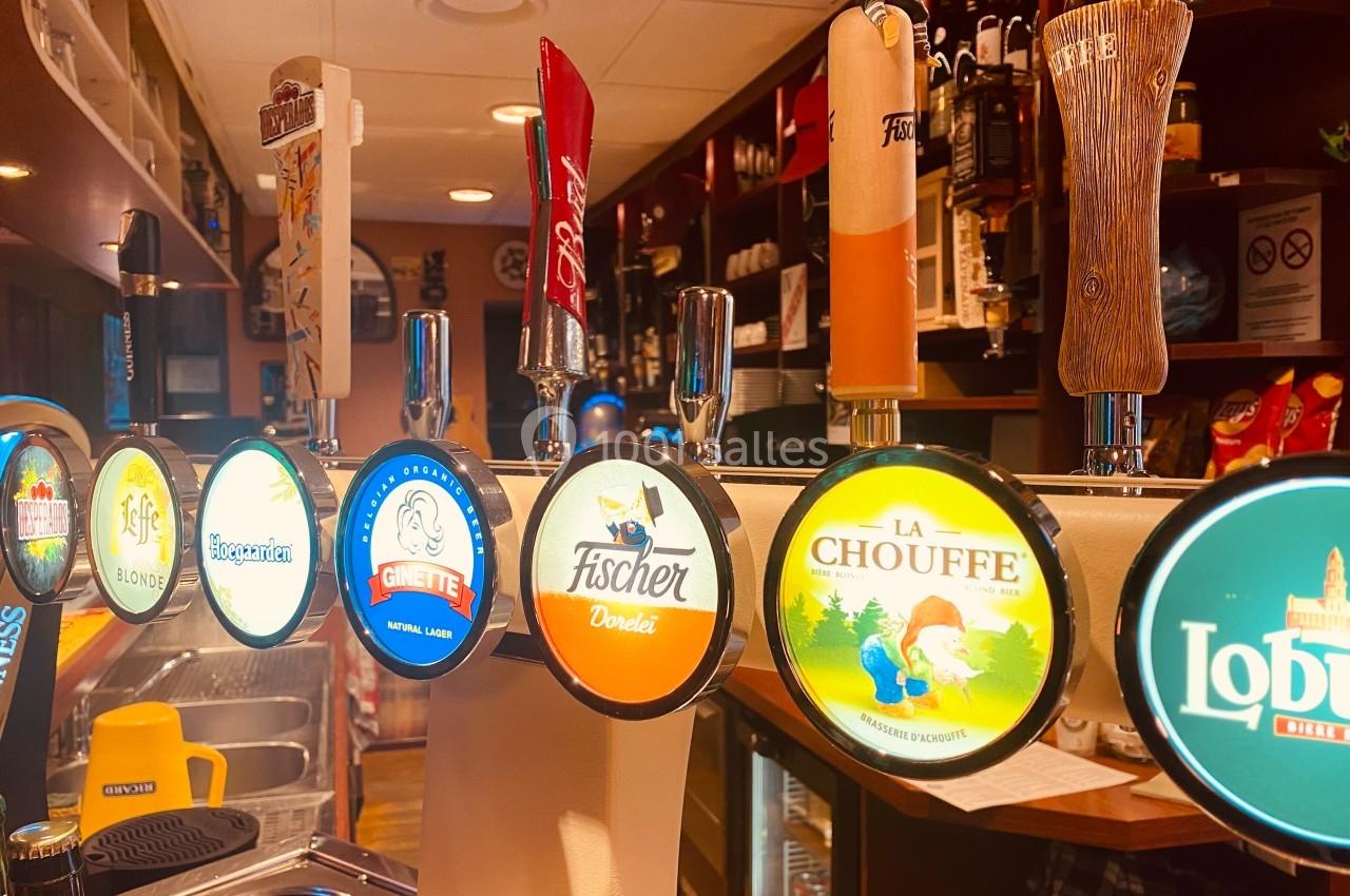 Tireuses à bière alignées dans un bar, avec différentes marques affichées sur les poignées colorées.