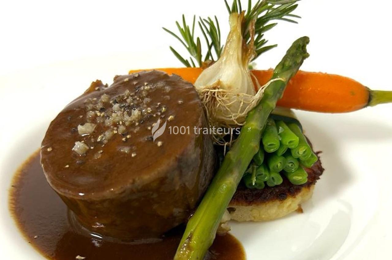 Plat composé d'un médaillon de viande en sauce, accompagné de légumes verts, carotte, oignon et herbes fraîches.