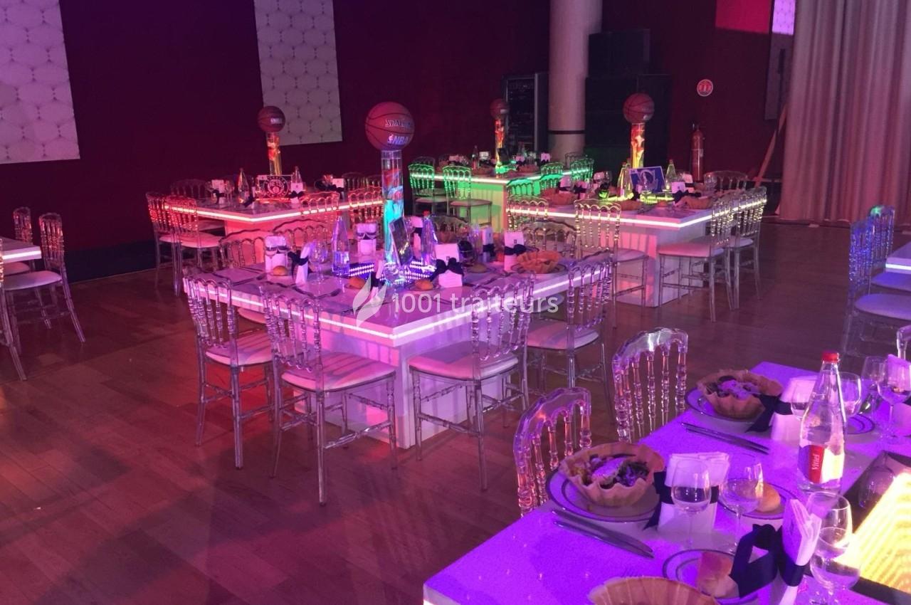 Tables décorées pour un événement, avec chaises transparentes, éclairage coloré et centres de table en forme de ballon de…