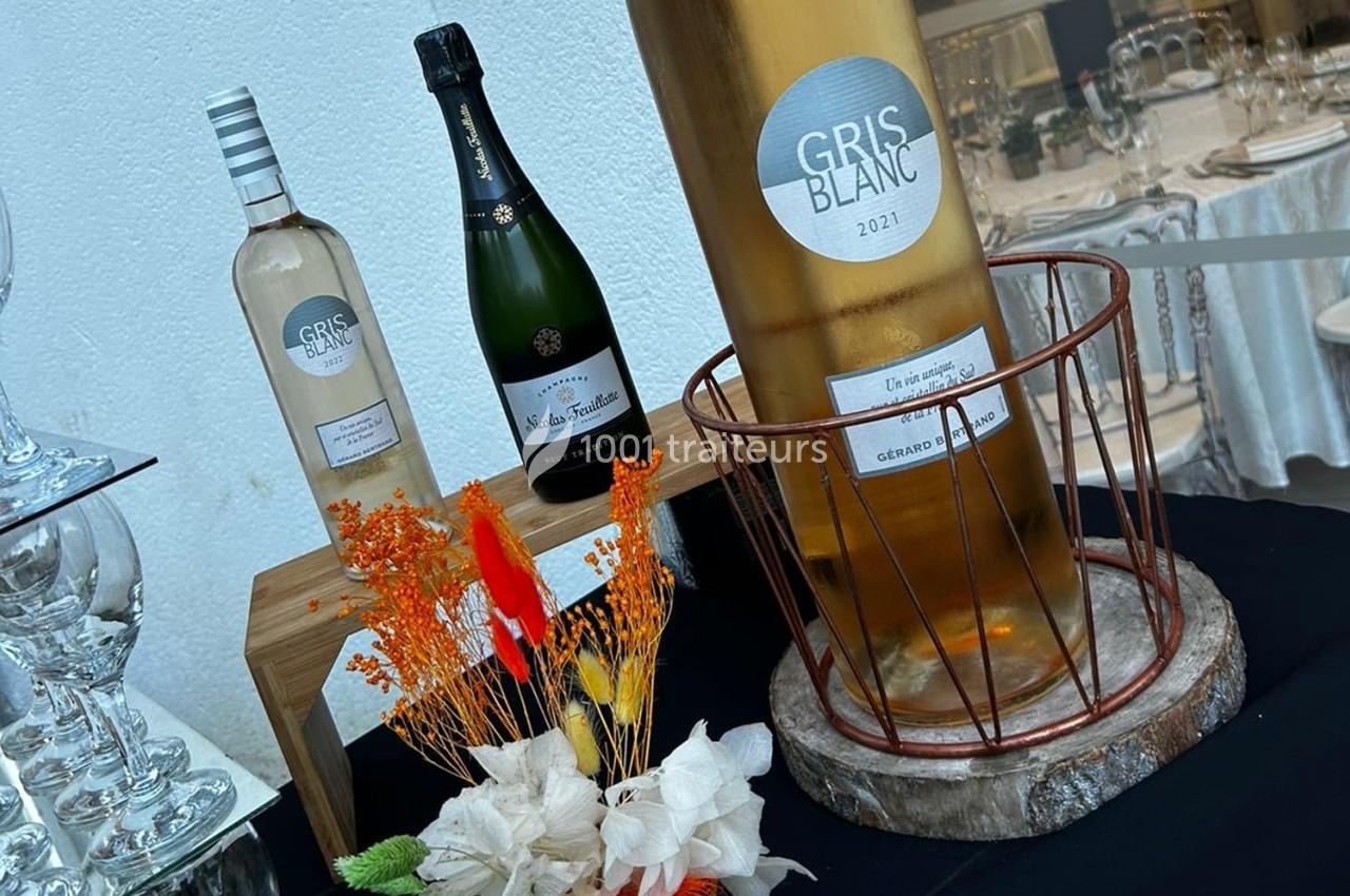Bouteilles de vin et de champagne exposées sur une table avec des fleurs séchées en décoration.