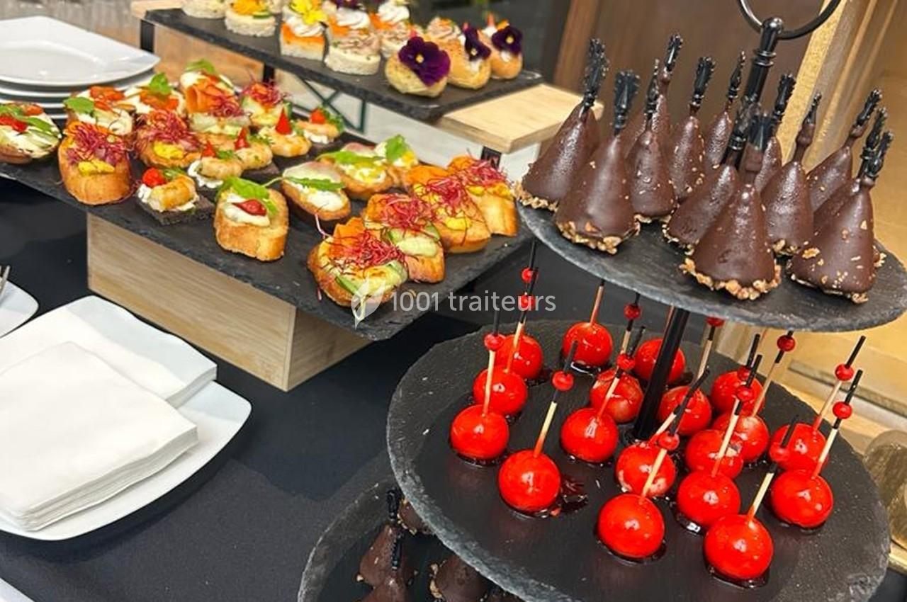 Plateaux de bouchées apéritives variées, incluant des toasts garnis, desserts enrobés de chocolat et billes rouges.