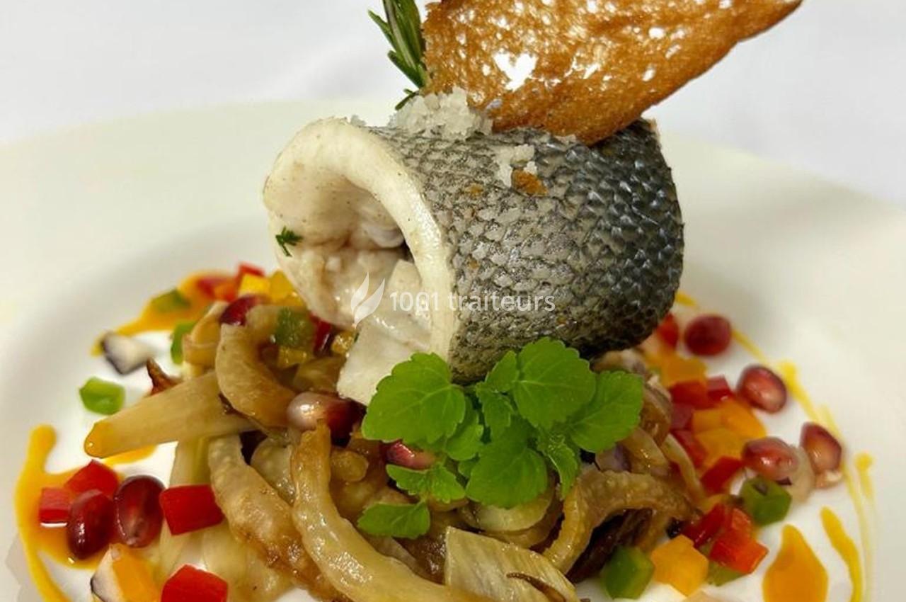 Filet de poisson roulé sur un lit de légumes colorés, garni de grenade, herbes fraîches et croûton doré.