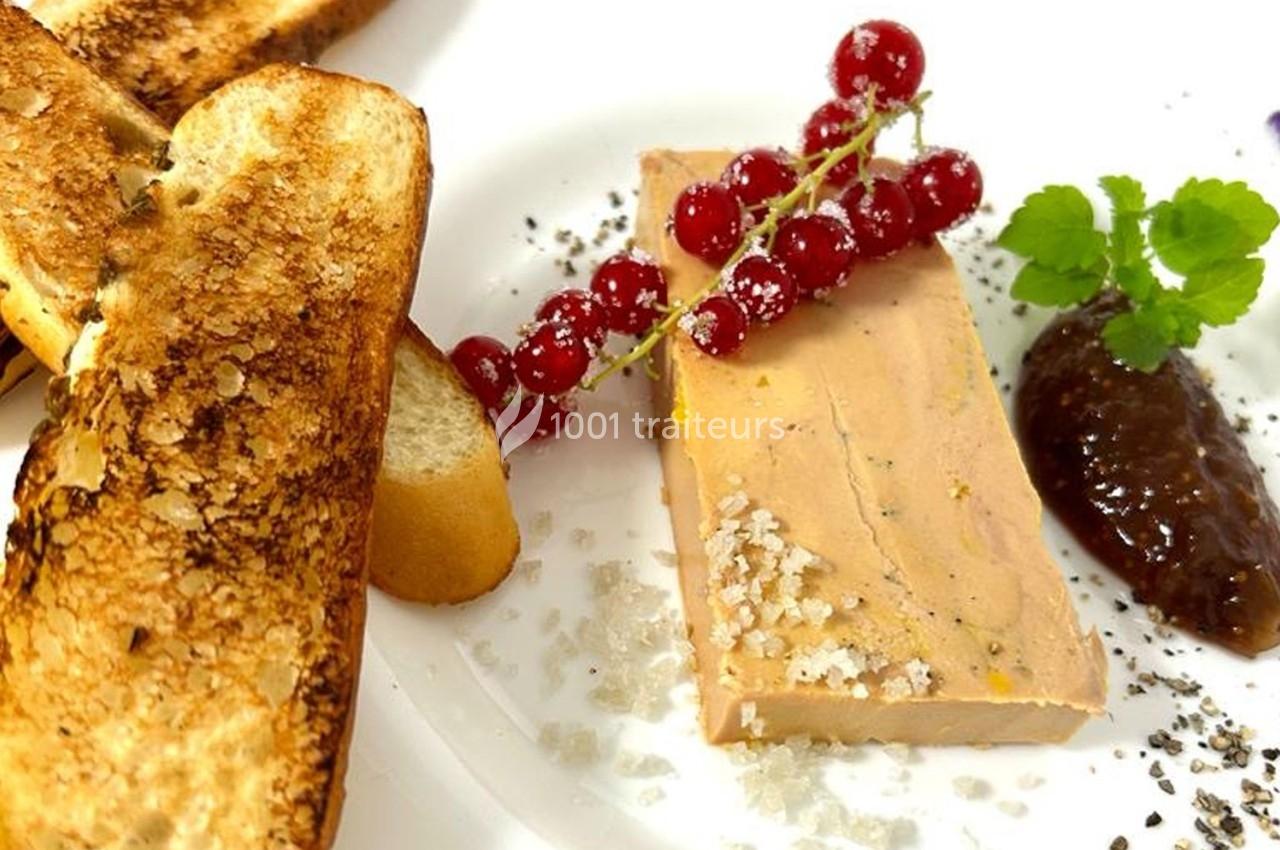 Tranche de foie gras avec groseilles, confiture et toasts grillés, présentée sur une assiette blanche.