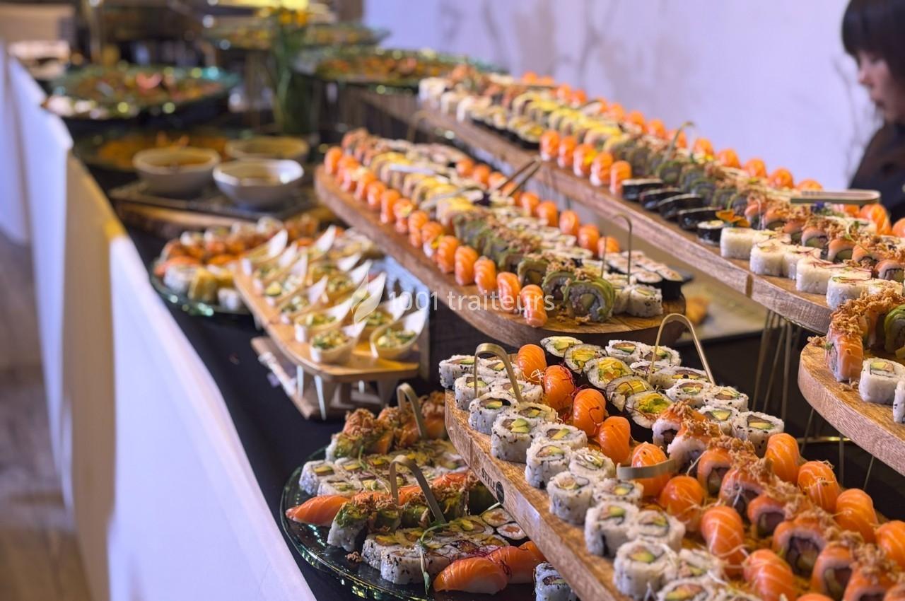 Plateaux garnis de sushis variés, alignés sur une table pour un buffet, avec des sauces en arrière-plan.