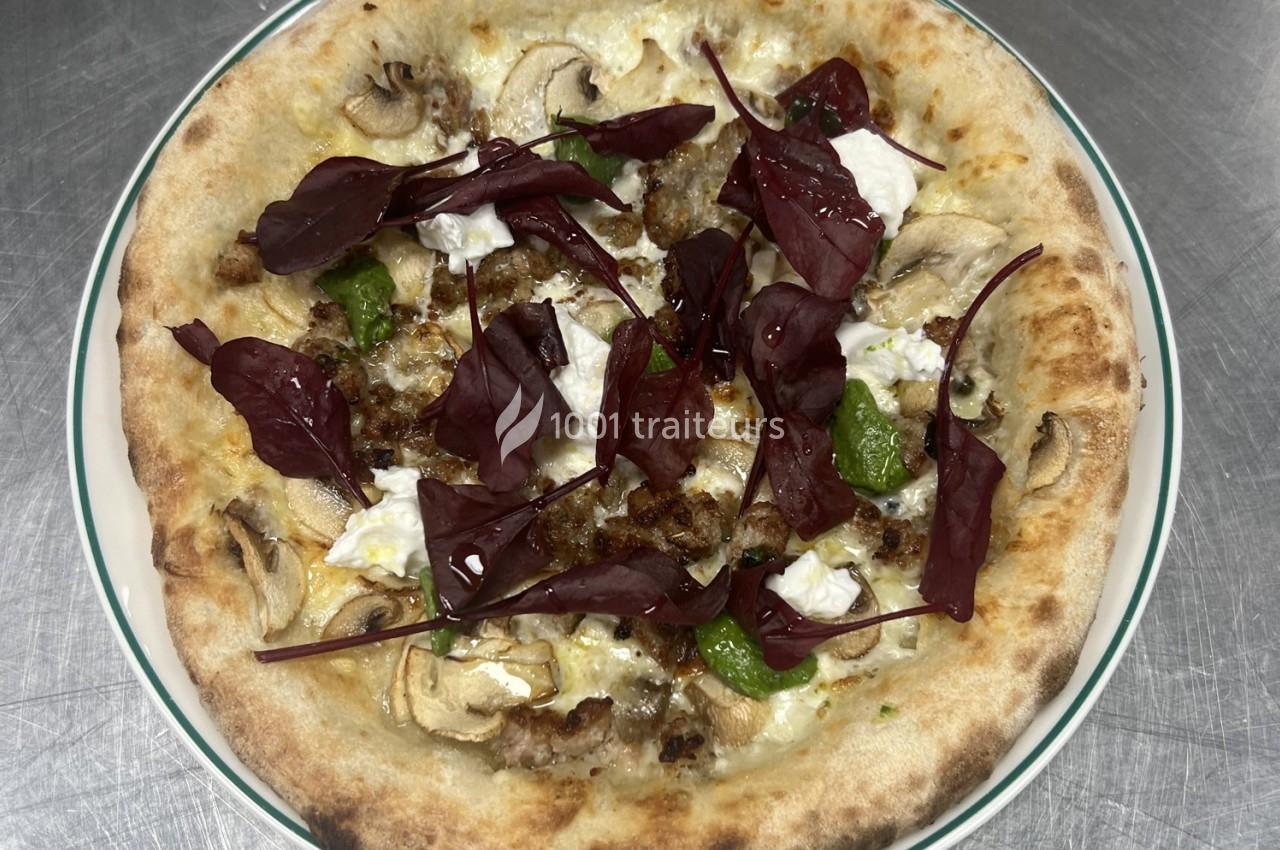 Pizza garnie de champignons, fromage frais, feuilles rouges et herbes, servie sur une assiette blanche.
