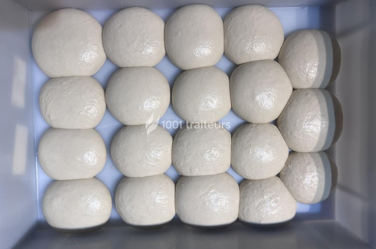 Boules de pâte crue alignées en rangées dans un bac rectangulaire.