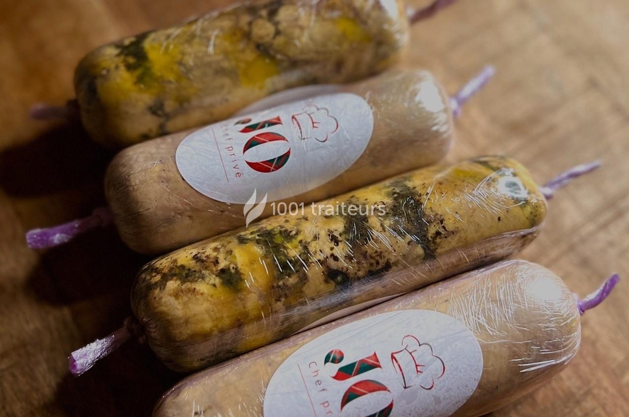 Quatre rouleaux de préparation alimentaire emballés sous vide, posés sur une surface en bois.