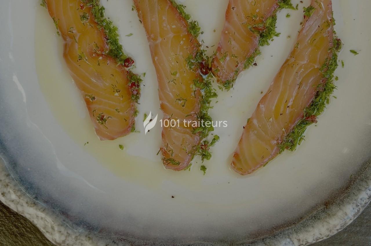 Tranches de saumon fumé disposées sur une assiette, garnies d'herbes fraîches et d'un filet d'huile.