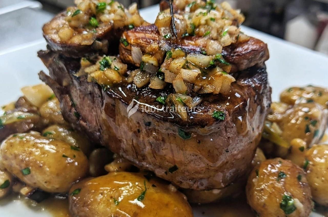 Plat de viande grillée garnie d'oignons et herbes, accompagné de pommes de terre rôties nappées de sauce.