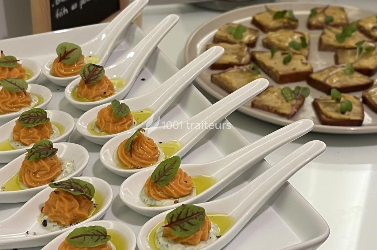 Cuillères apéritives garnies de mousse orange et herbes, accompagnées de toasts garnis sur un plateau.