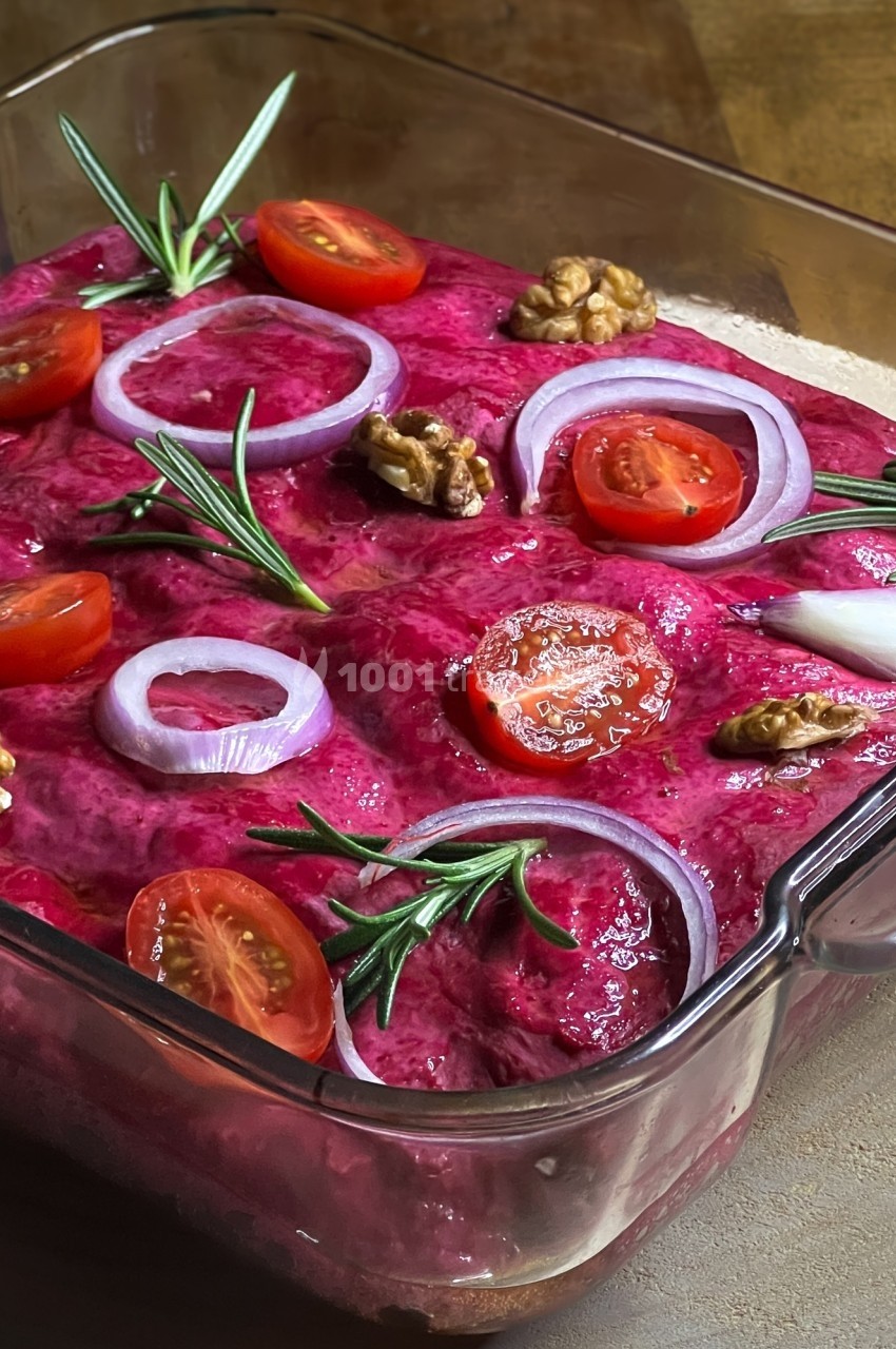 Plat de betterave crémeuse garni de rondelles d'oignon rouge, tomates cerises, noix et brins de romarin.