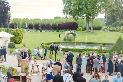 Chambre lumineuse avec lit double, parquet, rideaux orange, lustre et grandes fenêtres donnant sur l'extérieur.