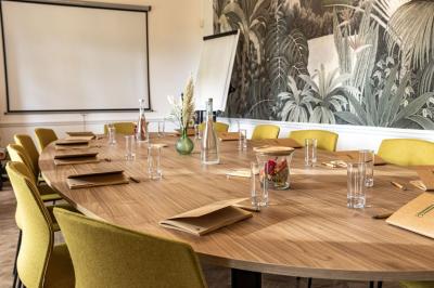 Chambre lumineuse avec lit double, parquet, rideaux orange, lustre et grandes fenêtres donnant sur l'extérieur.