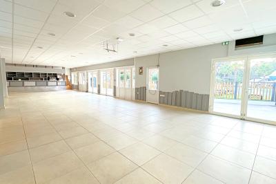 Un enfant avec des brassards orange glisse sur un toboggan rouge dans une piscine extérieure ensoleillée.