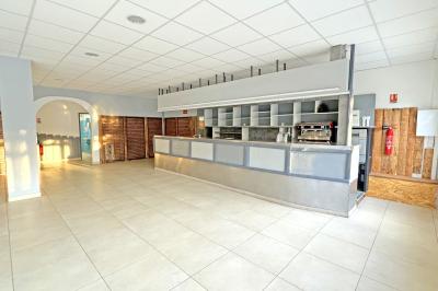 Un enfant avec des brassards orange glisse sur un toboggan rouge dans une piscine extérieure ensoleillée.