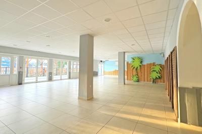 Un enfant avec des brassards orange glisse sur un toboggan rouge dans une piscine extérieure ensoleillée.
