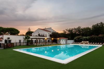 Un enfant avec des brassards orange glisse sur un toboggan rouge dans une piscine extérieure ensoleillée.