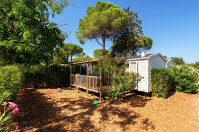 Un enfant avec des brassards orange glisse sur un toboggan rouge dans une piscine extérieure ensoleillée.