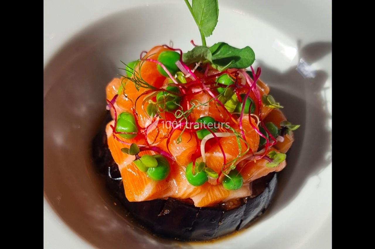Tartare de saumon frais sur lit d'aubergine grillée, garni de pousses et de petits pois.