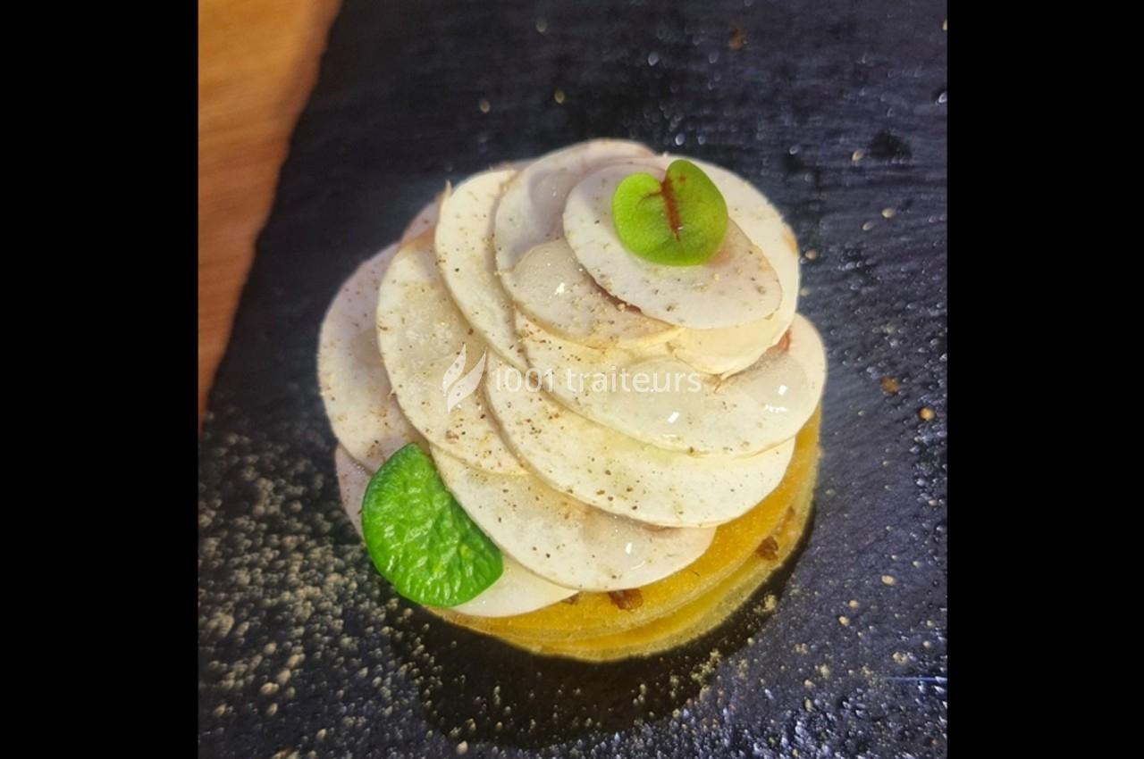 Tranches fines de champignons disposées en rosace sur une base jaune, garnies de feuilles vertes et d'assaisonnement.